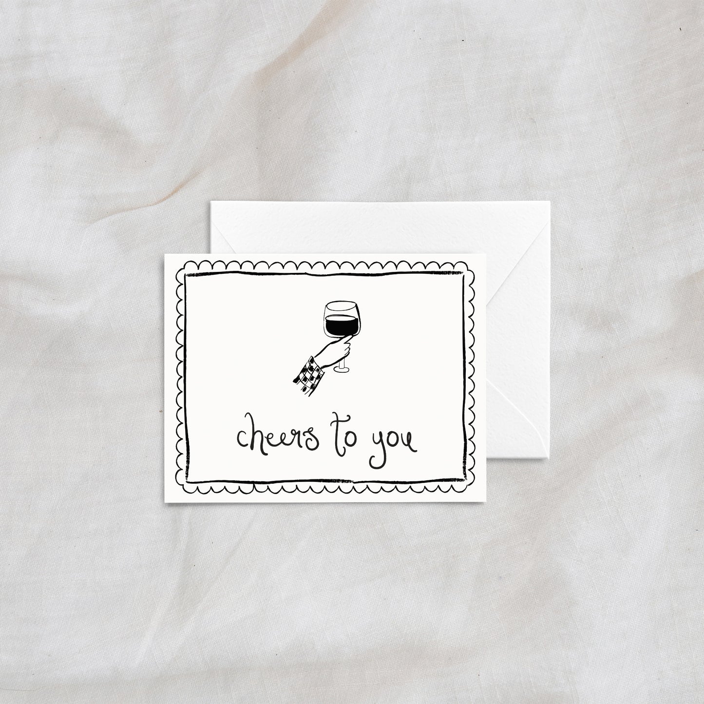 A stylish and modern greeting card with the phrase "cheers to you," showcasing a hand-drawn illustration of a hand holding a wine glass. The card includes an elegant scalloped border and is paired with a white envelope, ideal for weddings, anniversaries, or celebratory messages.